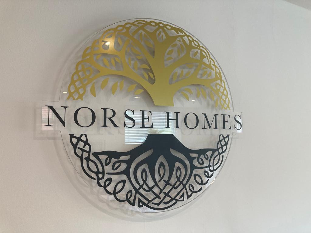Clear perspex stand off sign on office wall with Norse Homes branding